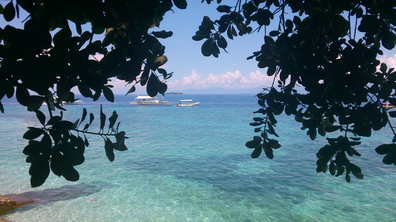 view over the reef of Moalboal, with some outrigger dive boats and Pescador Island in the background